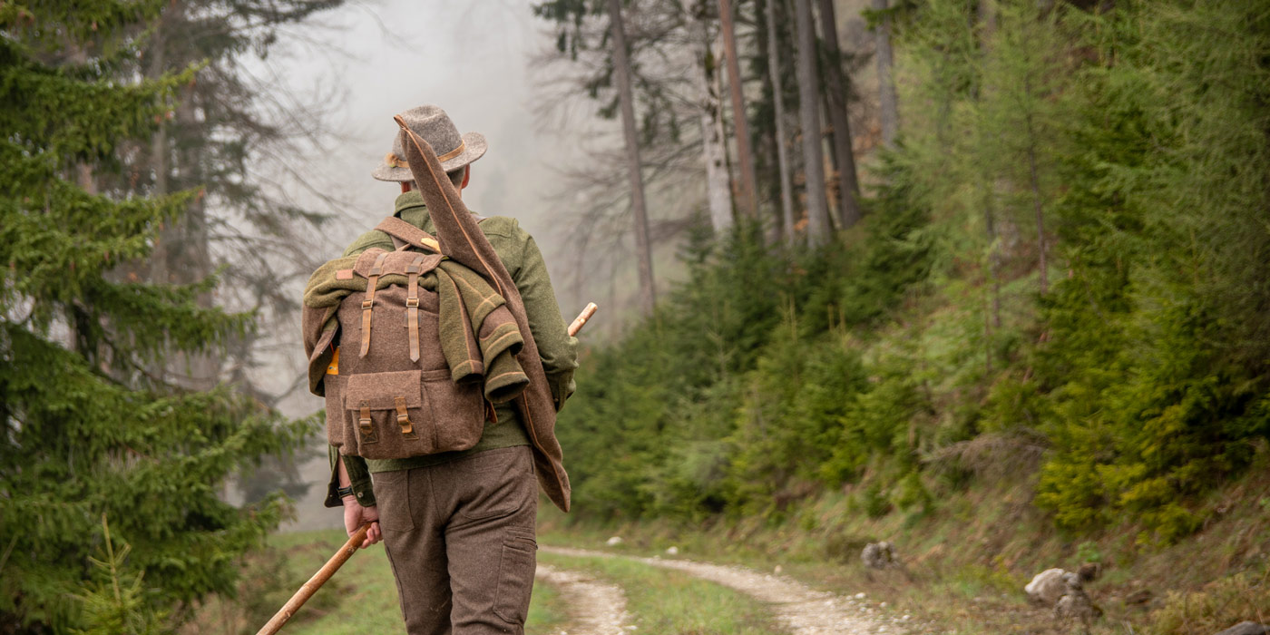 Jagdausrüstung für Jäger Jäger mit Ausrüstung auf Bergweg