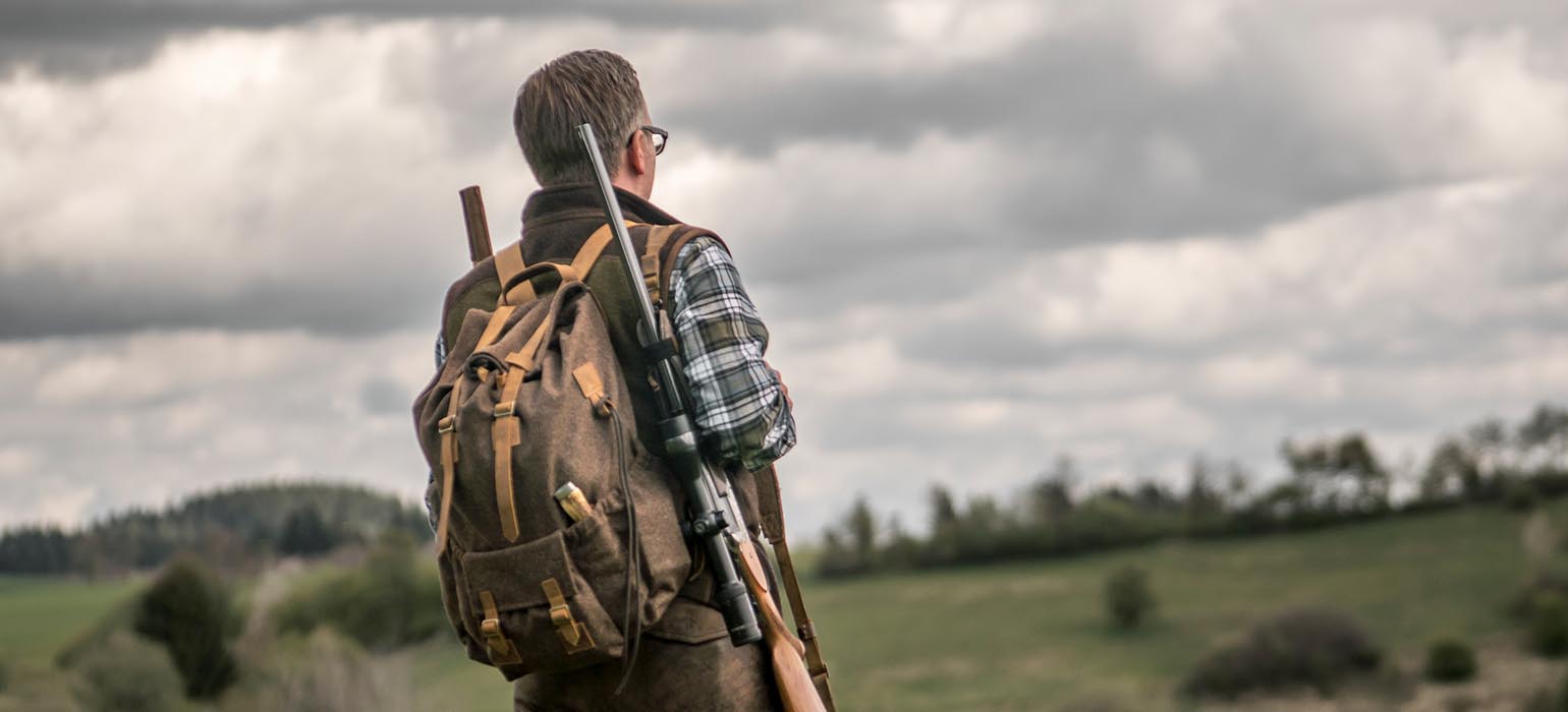 Jäger mit Jagdrucksack an Wiese Jäger mit Jagdrucksack am Feld