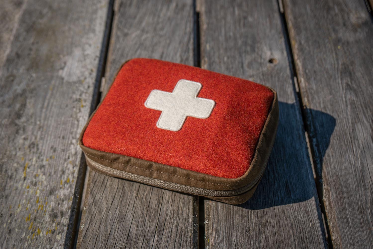 Geschlossenes Erste-Hilfe-Set Rotes Erste-Hilfe-Set aus Loden auf Dielenboden