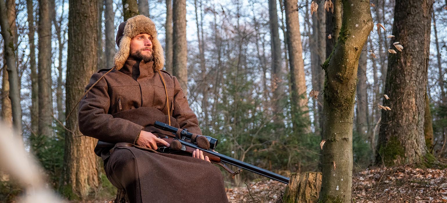 Jäger auf Drückjagdansitz Jäger sitzt im Wald